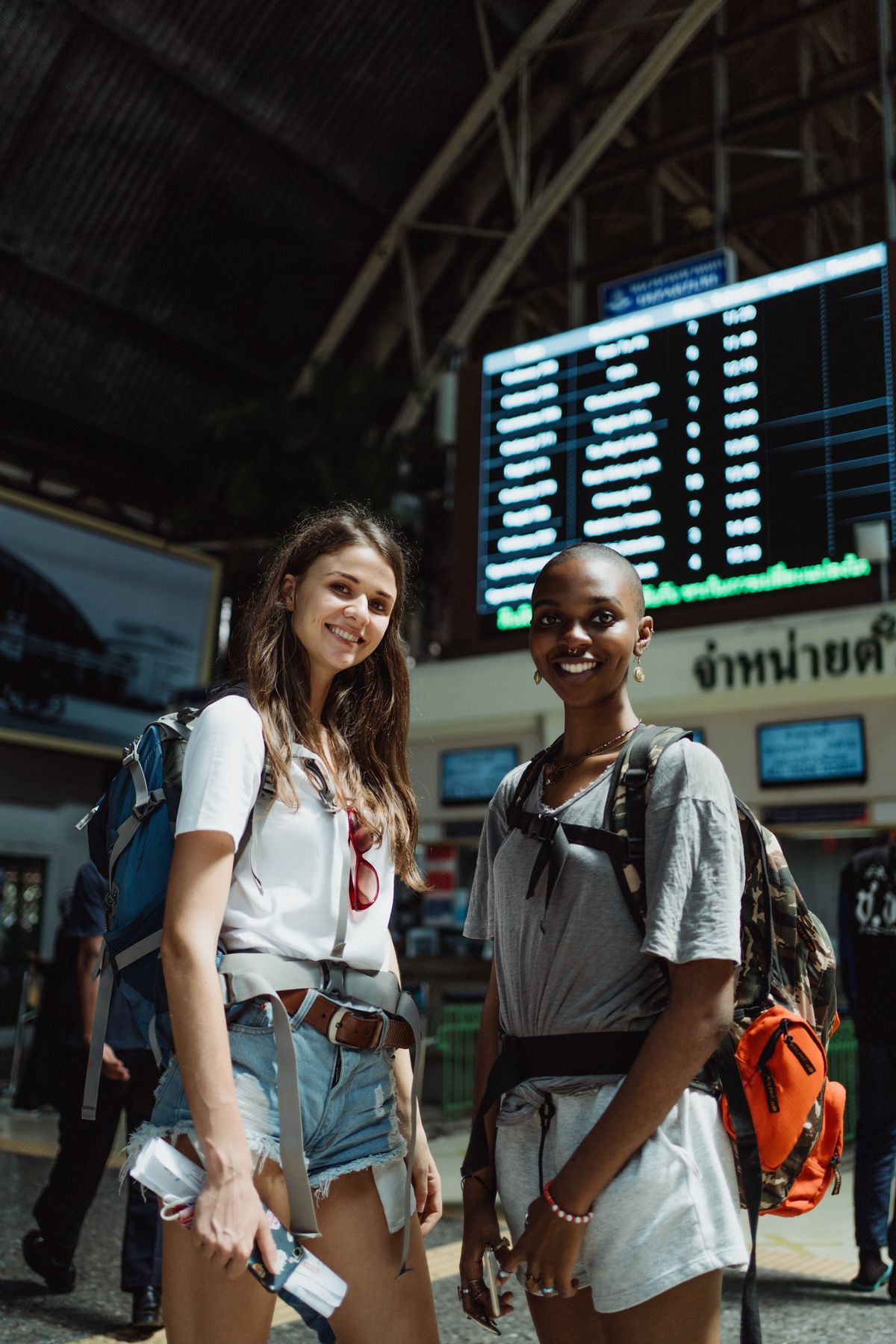 Two travelers under a station departures board