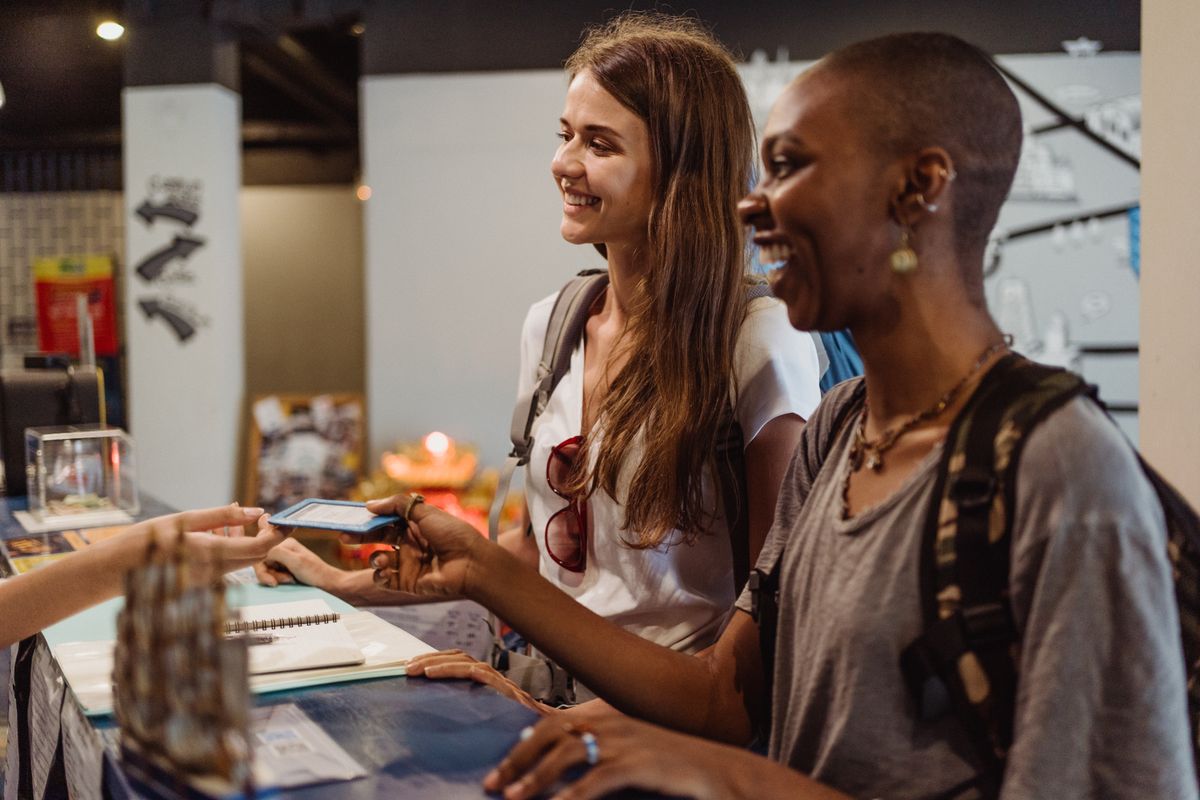 A cashier handing a printed ticket to a smiling passenger at the counter